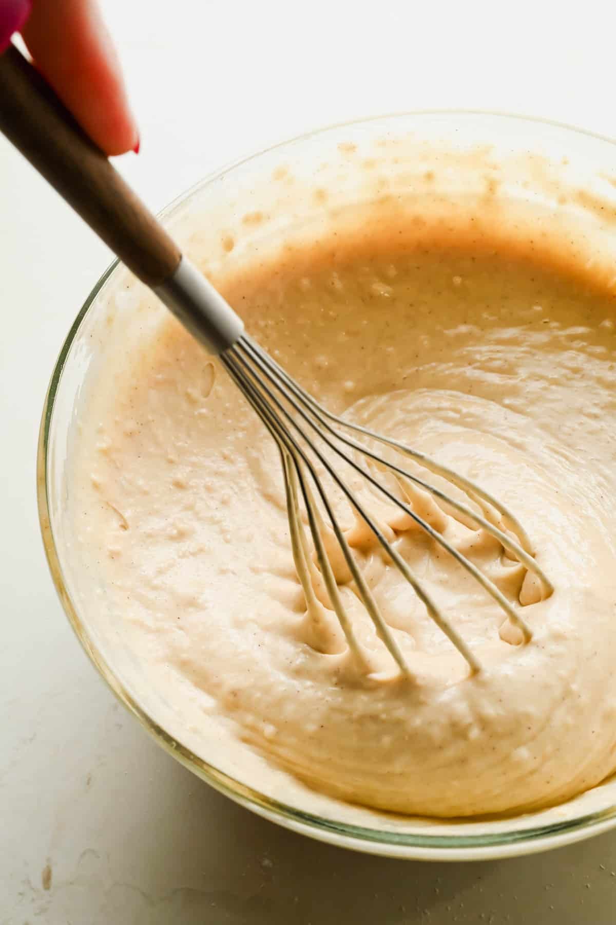 Almond sheet pan pancake batter being whisked in a glass bowl.