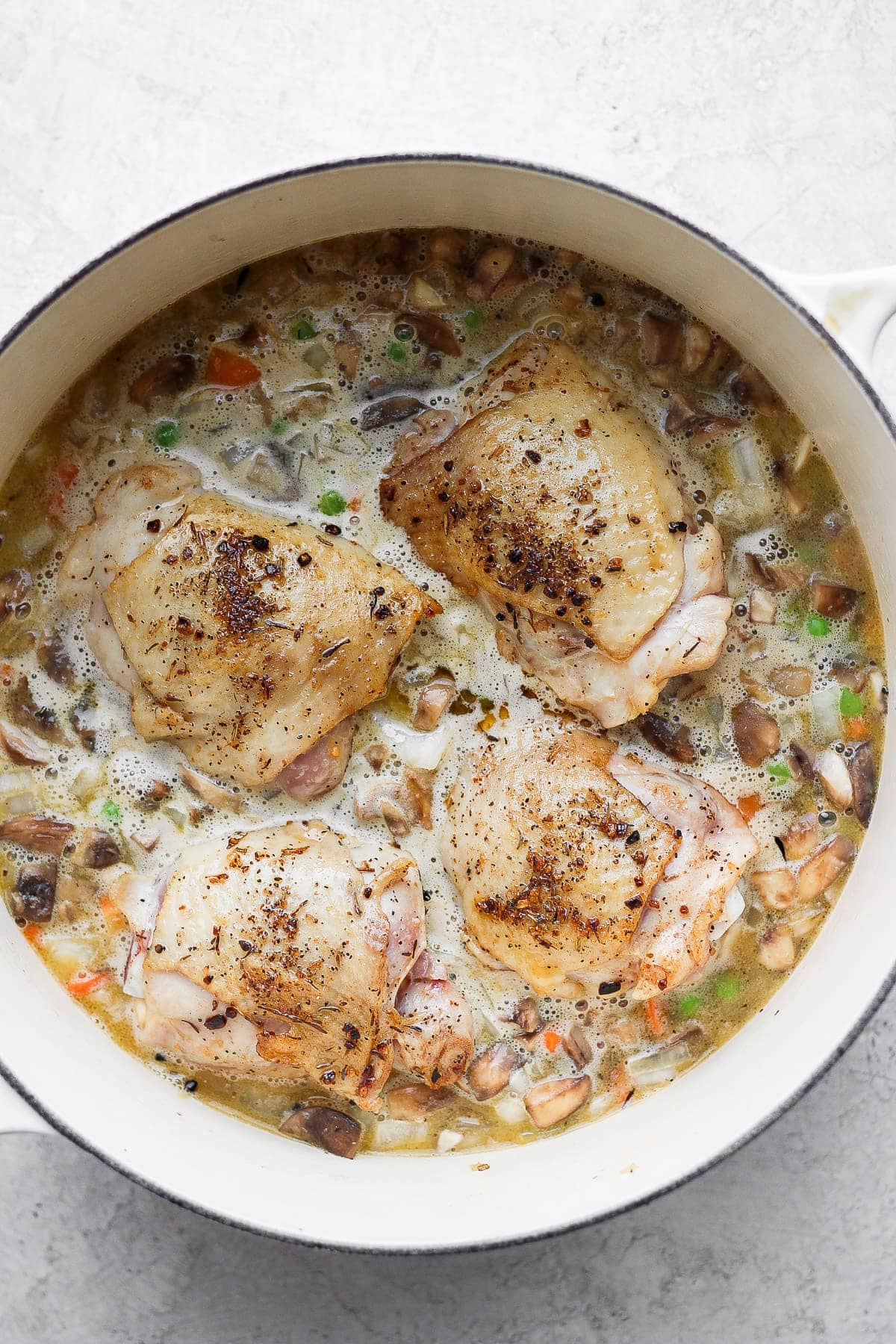 A flavorful chicken and rice recipe made with juicy chicken thighs and the most flavorful rice medley you've ever had! And, yes, it includes tons of veggies! uncooked rice with seared chicken thighs on top.
