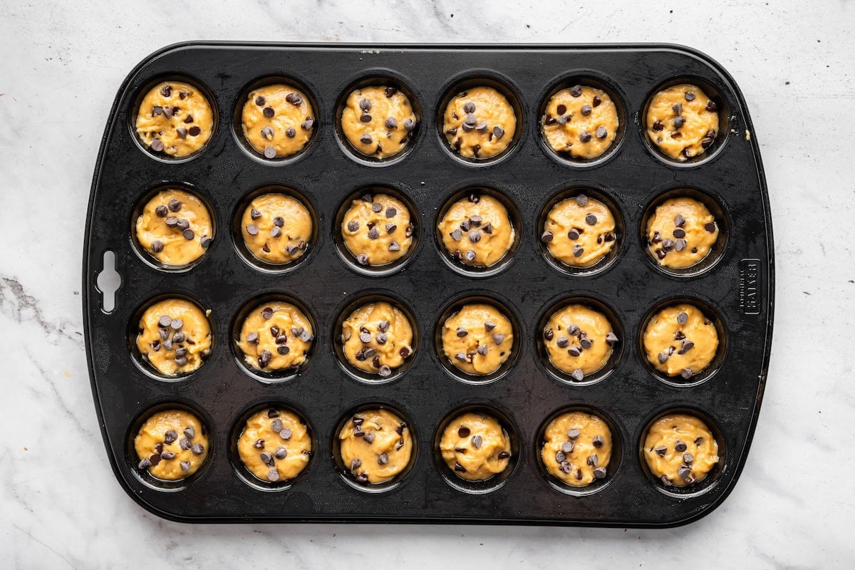 Mini chocolate chip muffin batter in a muffin tin.