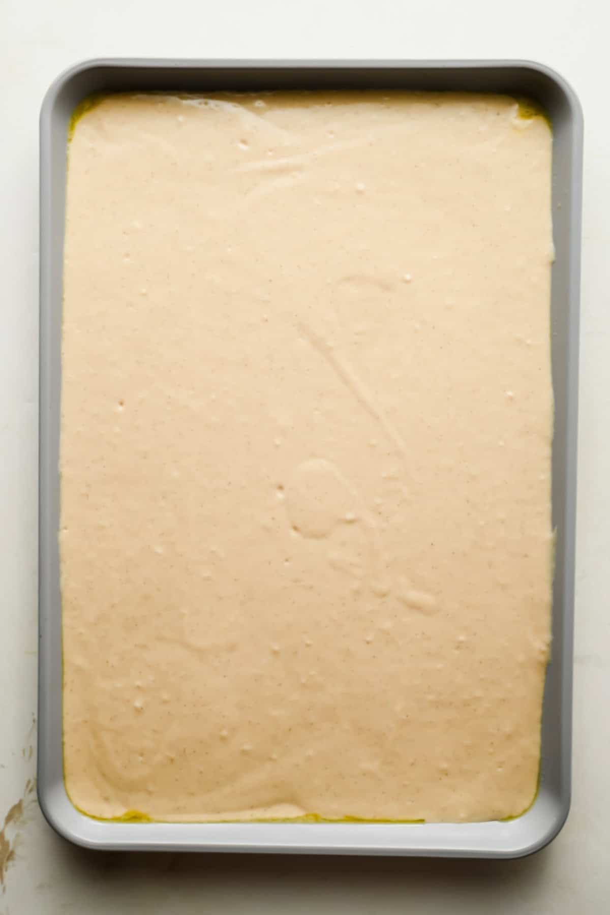Pancake batter spread evenly in a greased quarter sheet pan.