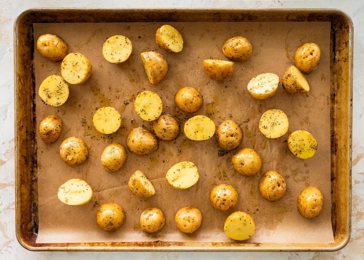 Halved baby potatoes on a baking sheet.