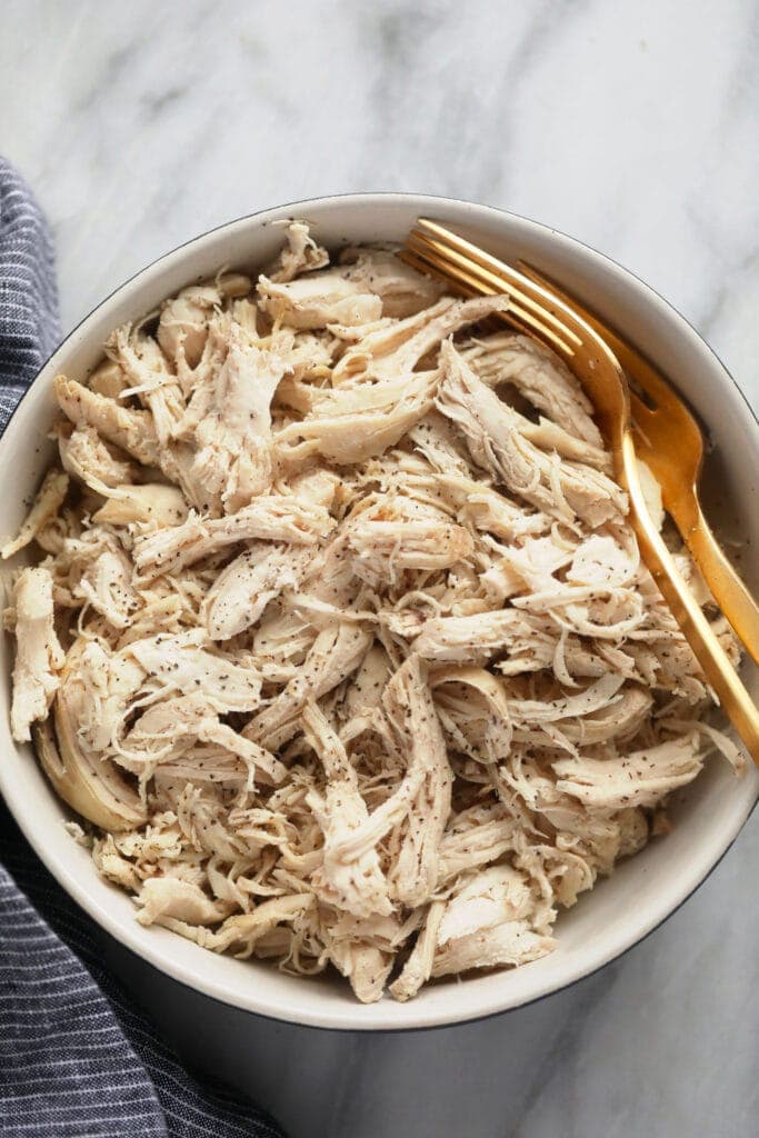 Wondering how to make shredded chicken in the Instant Pot? Look no further! This easy Instant Pot Shredded Chicken recipe is ready in less than 20 minutes, and will easily become a meal-prep staple in your home. instant pot shredded chicken in a bowl.